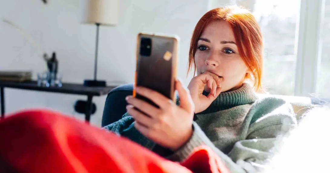Person sitting on a couch and looking at their mobile phone