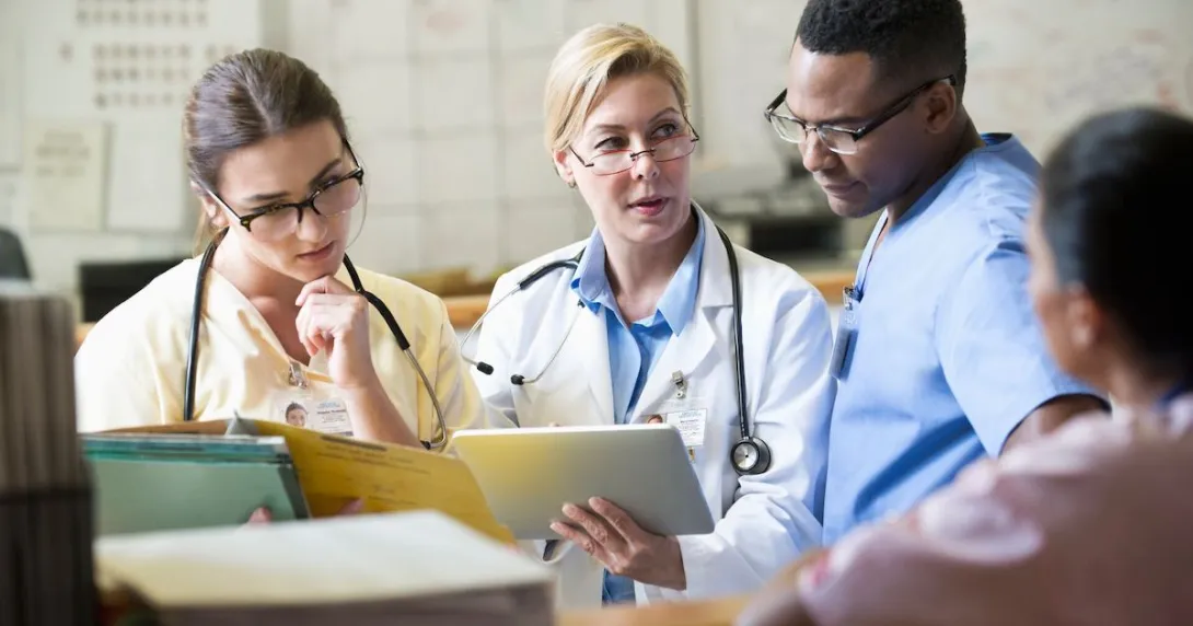 Healthcare providers sitting in a room and looking at a tablet