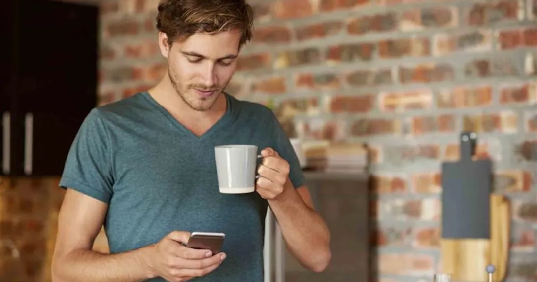 Cellphone user holding a cup of coffee while walking around