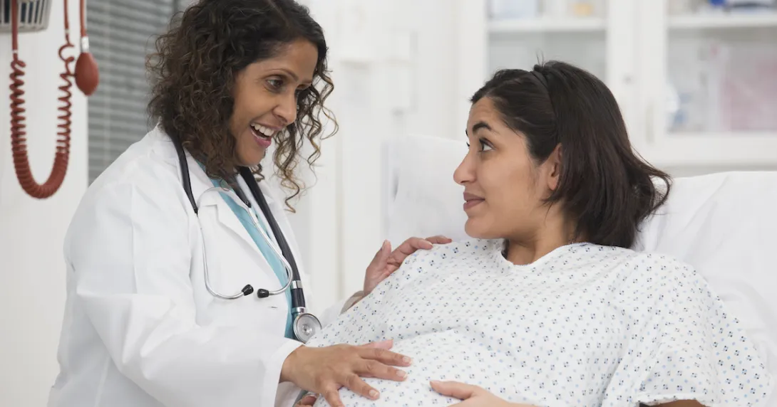 Pregnant person in a hospital bed with a doctor standing next to them