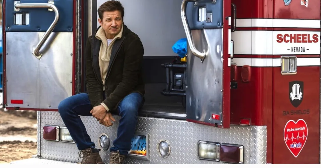 Jeremy Renner sitting on the back of an ambulance