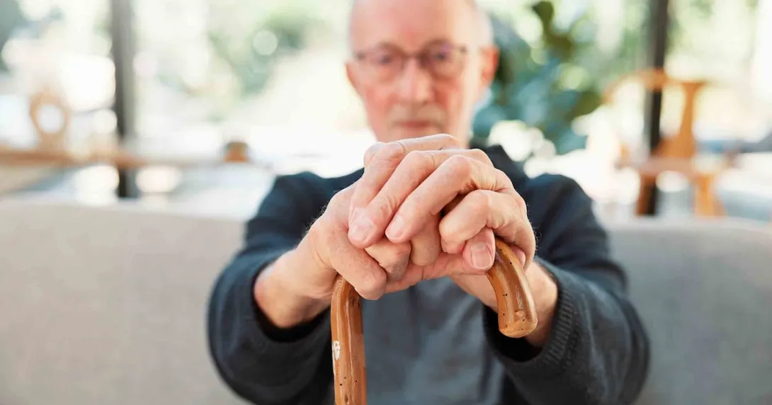 Person sitting down while holding a cane in front of them