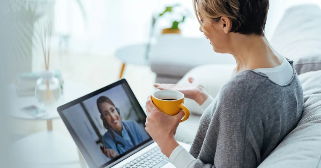 Person sitting on a couch with a laptop on a telehealth video call