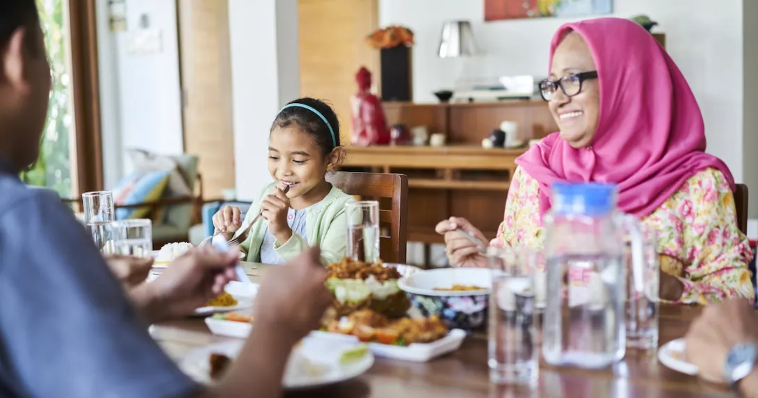People sitting around a dinner table with food on it