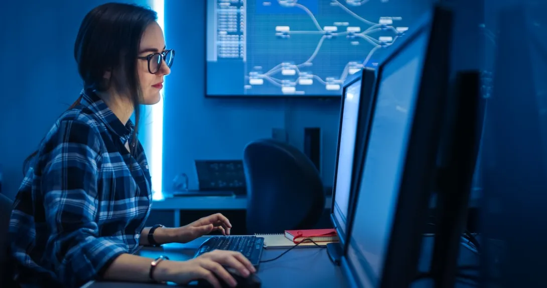 Person sitting at a computer while in a dark room