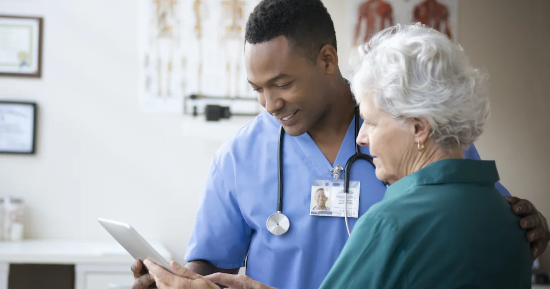 A nurse helping a senior patient use a digital tablet