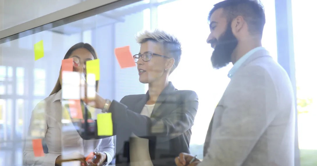 People standing in a room looking at Post-its on a wall
