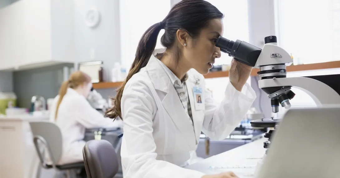 Healthcare professional looking into a microscope