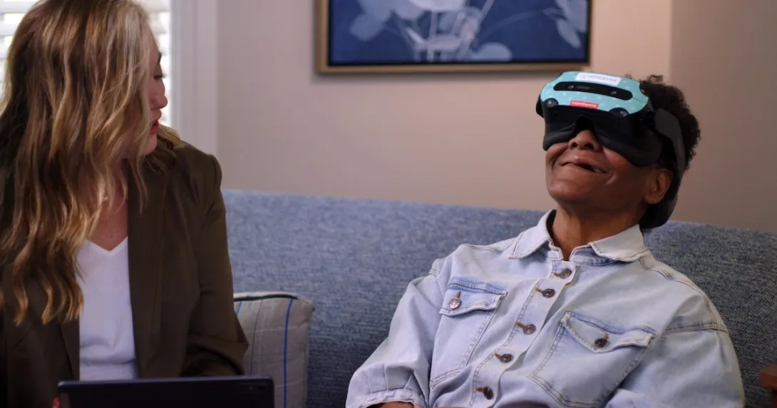 Patient using a Rendever headset while sitting next to another individual