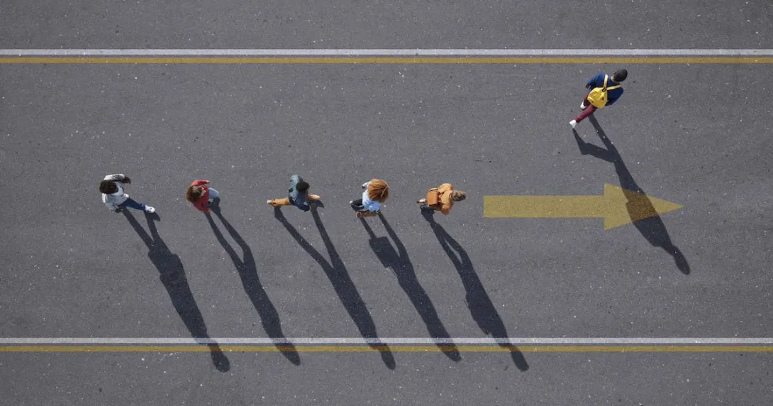 People walking in a line with one person walking elsewhere