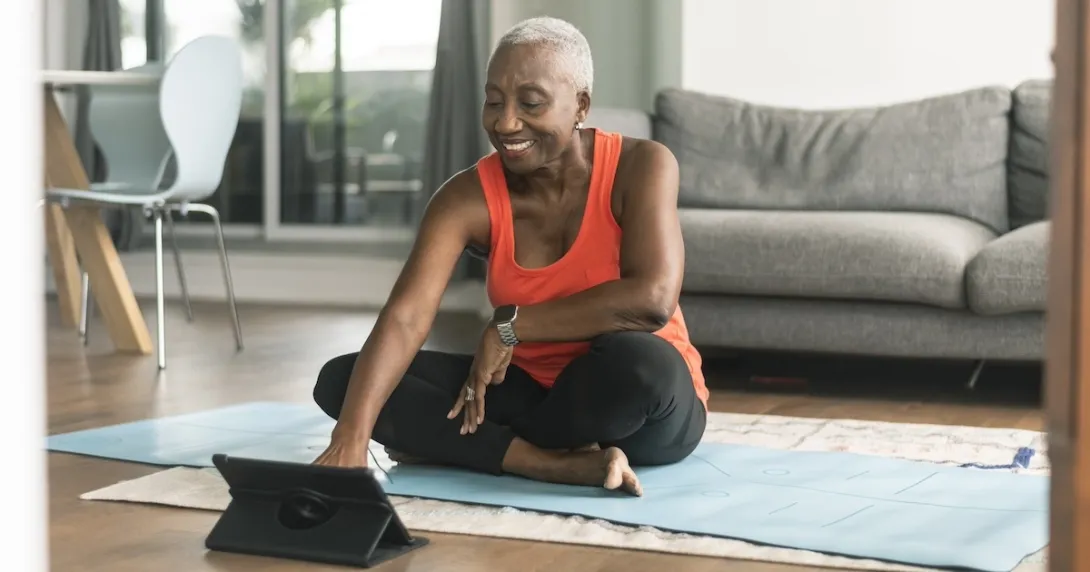 Person sitting on exercise mat interacting using a tablet