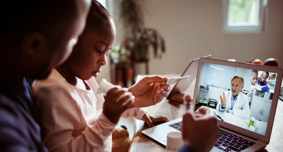 Close up of a father and daughter having a video call with their doctor