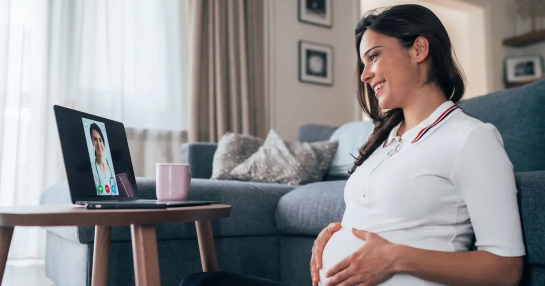 A pregnant person talking to a provider on a tablet