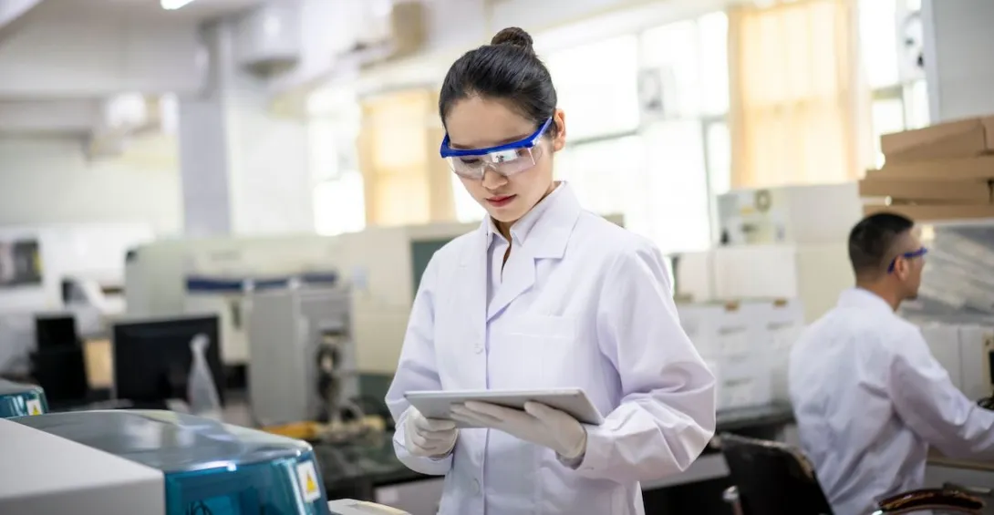 A researcher in a lab looking at a tablet