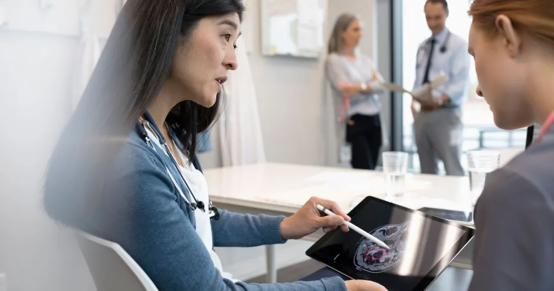 Two people looking at a tablet with an ultrasound image of a brain on the screen