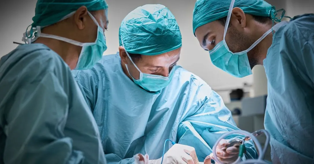 Surgeons in an operating room huddled around a patient on an operating table