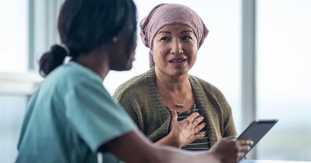 Healthcare provider sitting next to a patient while both look at a tablet