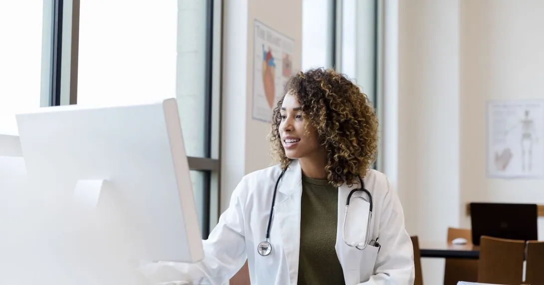 Healthcare provider sitting at a desk while looking at a computer