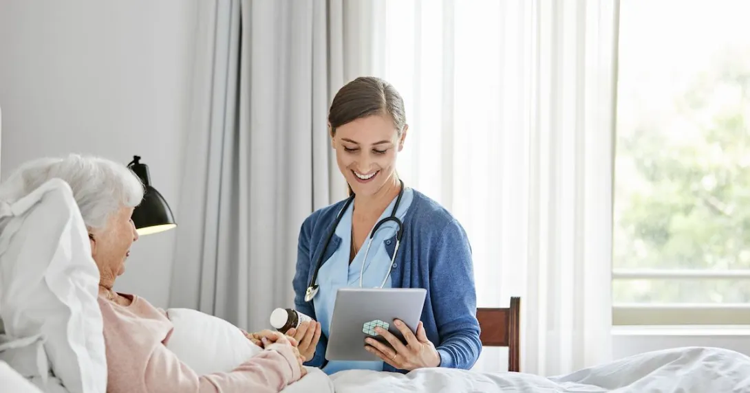 Healthcare provider in a patient's home sitting next to a patient lying in bed