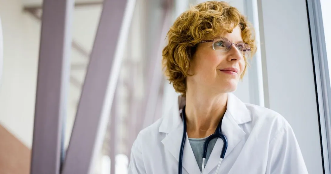 Healthcare provider wearing glasses and a stethoscope while looking to the side