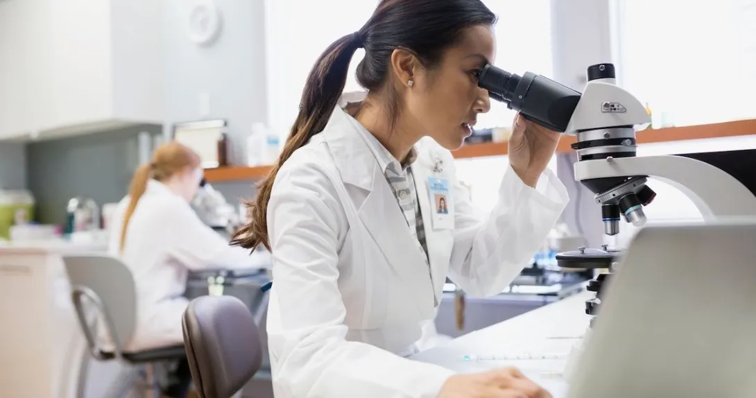 Scientist in a lab looking into a microscope