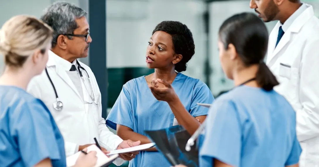 Five healthcare providers standing in a circle, talking to each other