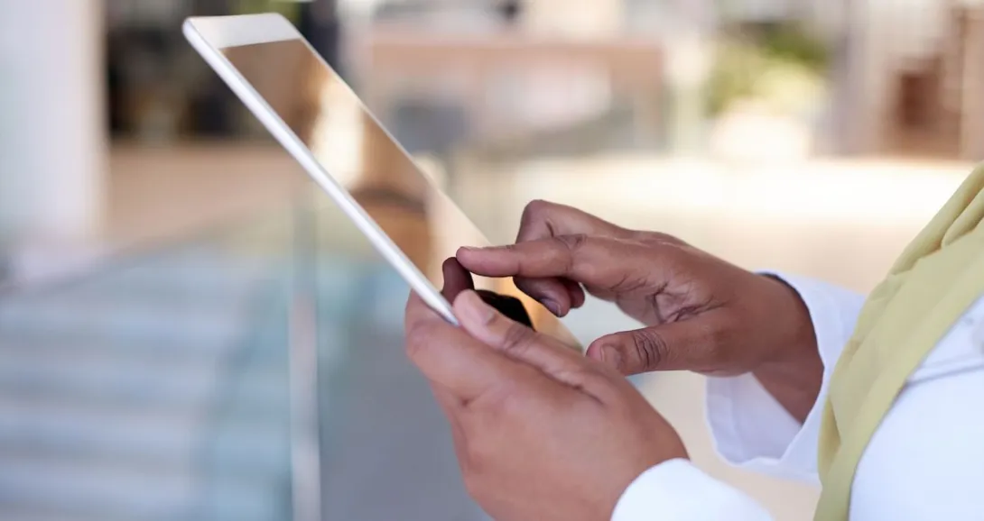 Person wearing a yellow scarf while holding a tablet