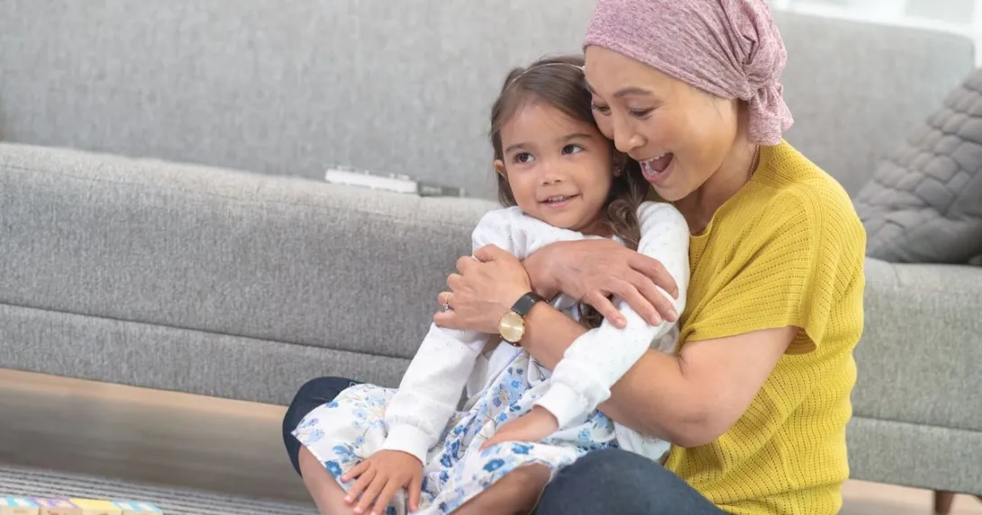 Person sitting on the floor holding another person in their hands while wearing a head scarf