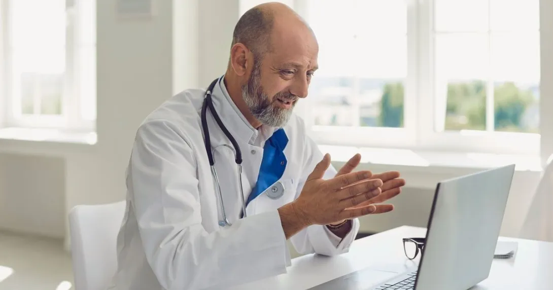 A doctor conducting a virtual consultation with a patient using a laptop