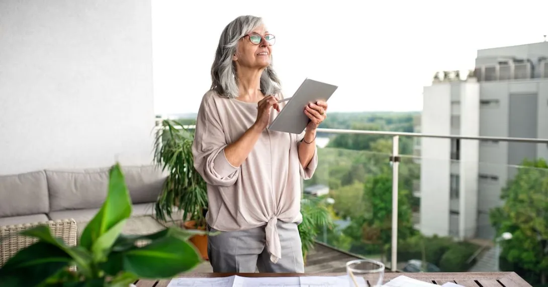 Person standing on a balcony with a tablet in their hand