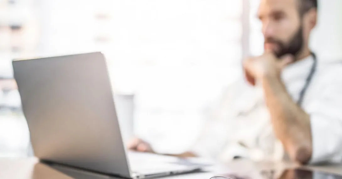 Healthcare provider sitting at a desk and looking at a computer