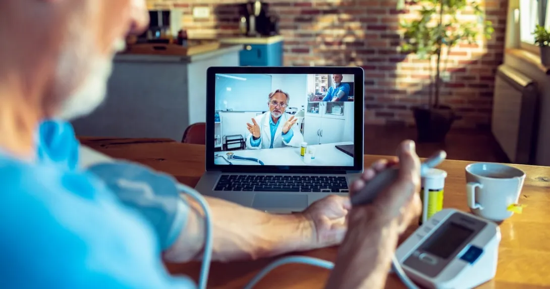 A doctor on screen guiding a patient measuring their blood pressure remotely