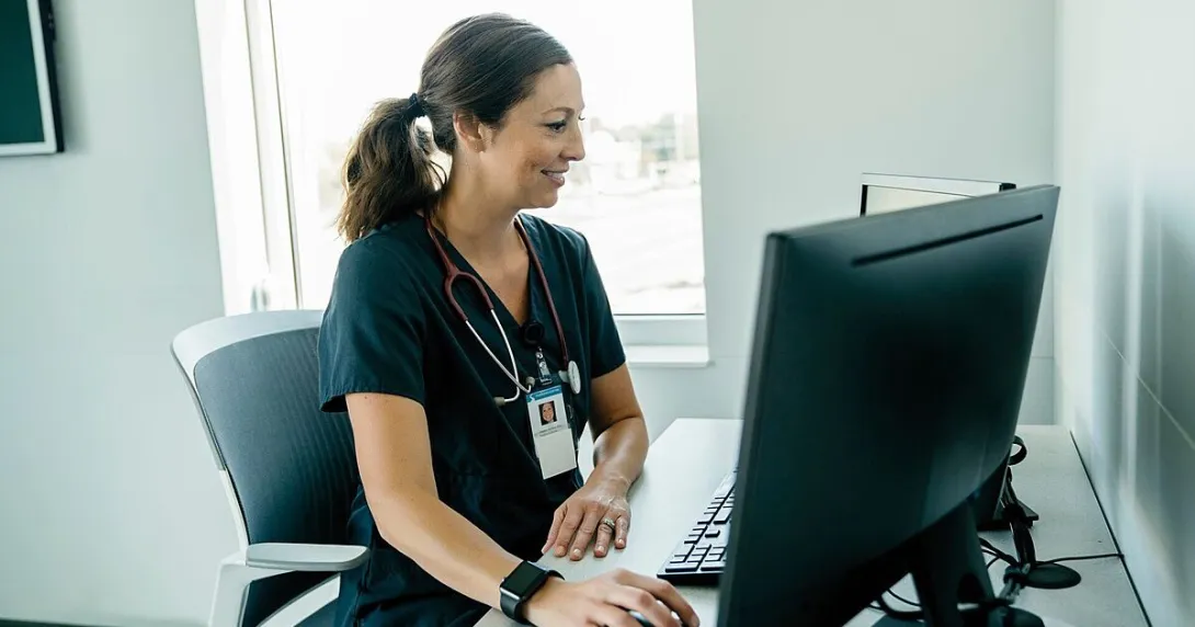 A doctor reviewing a patient's record on a desktop computer