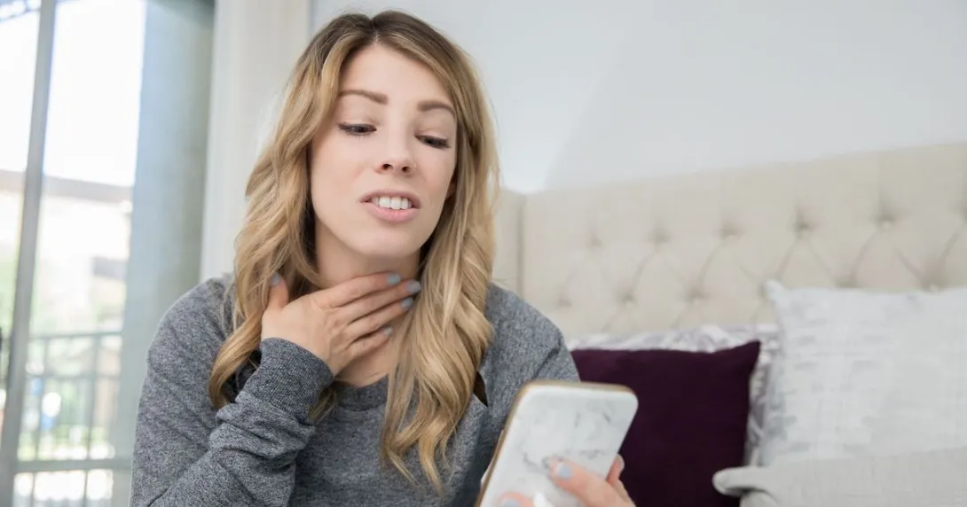 A person talking on a video chat on a phone about a sore throat